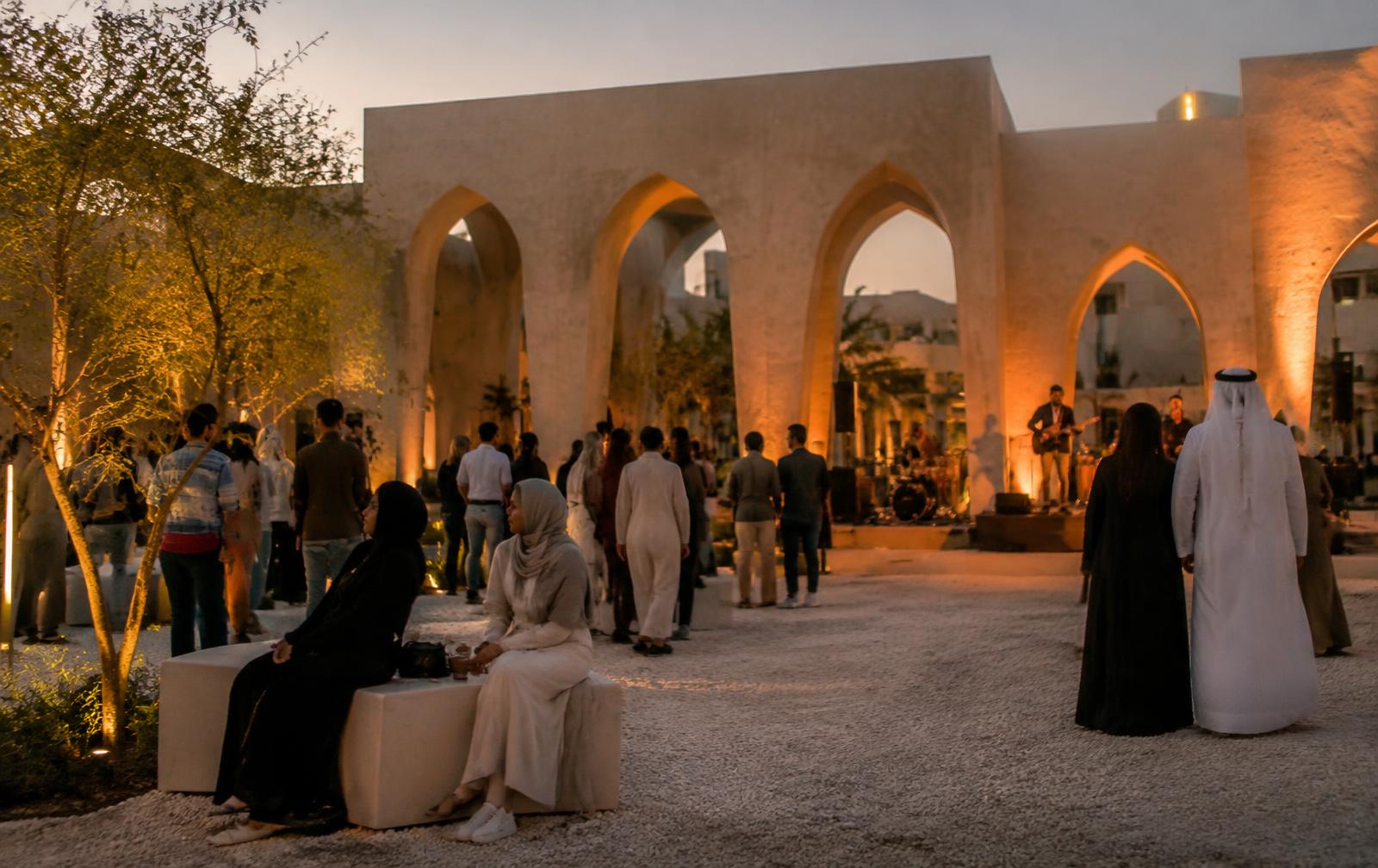 Crowd at an evening festival beneath stone arches